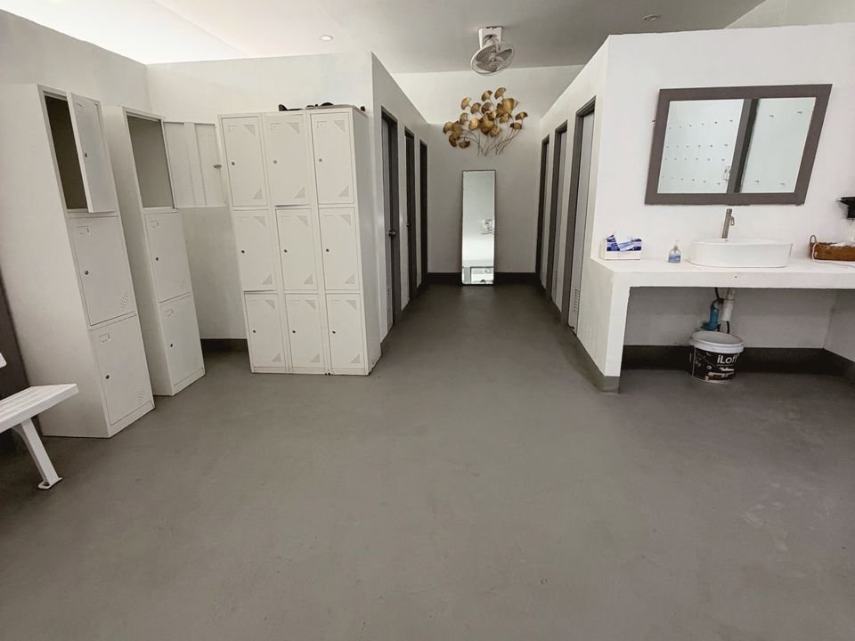 Changing room with white lockers, a full-length mirror and a washbasin