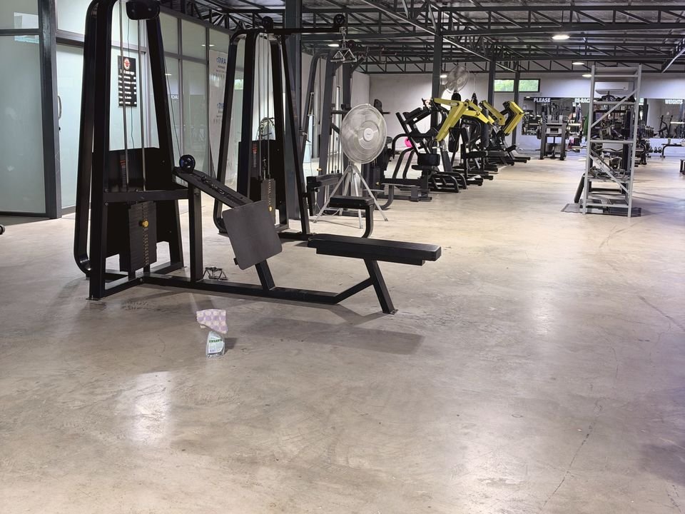 A weight-stack machine in front of a row of black and yellow plate-loaded machines