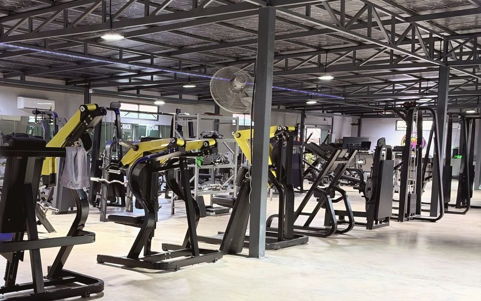 Warehouse-style gym in Jomtien with plate-loaded machines and a steel-truss roof