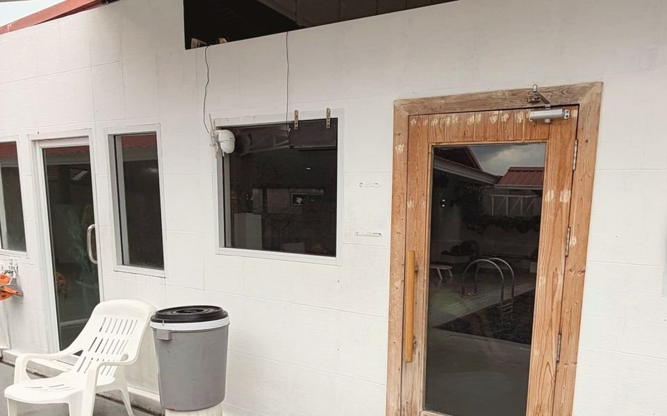 Sauna and steam room block by the pool, with a wooden door and sandals outside