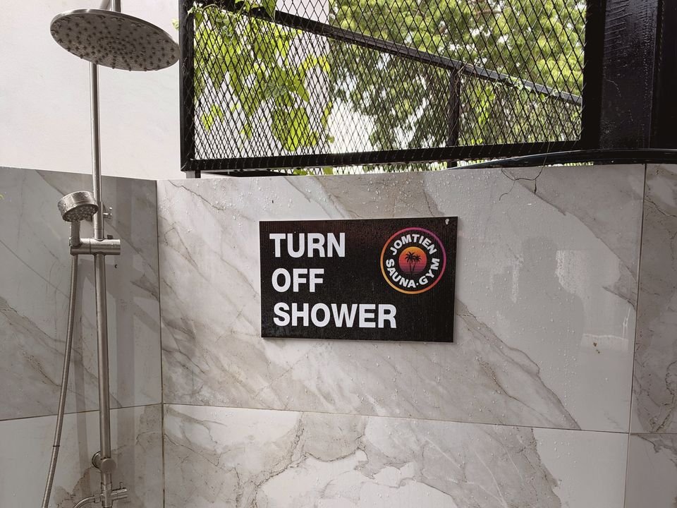 Rain shower on a marble-effect wall with a “Turn off shower” sign